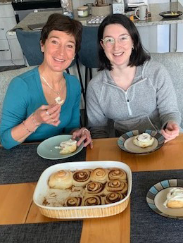 A mother and daughter sit enjoying freshly baked cinnamon buns together.
