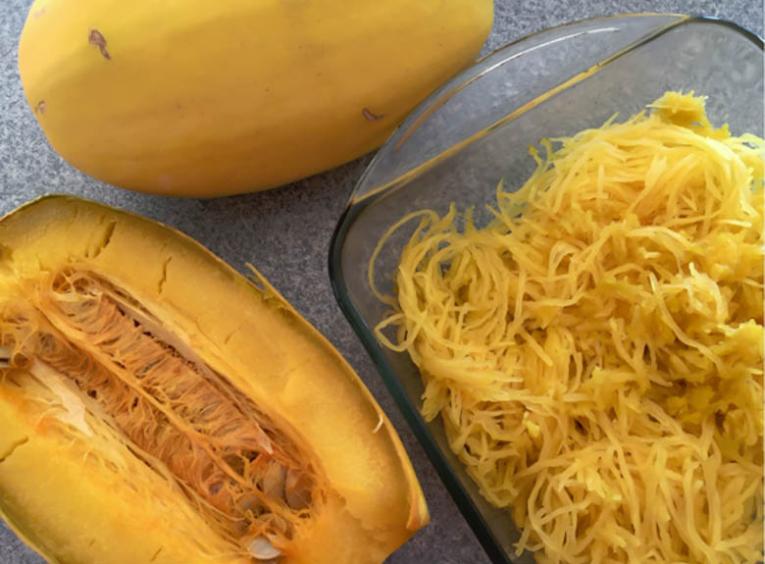 An opened spaghetti squash and the inside 'noodles' in a dish.