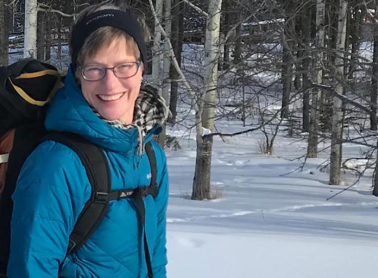 Woman on a trail hiking in snow during winter.