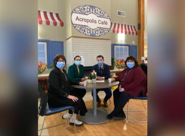Four Northern health employees, including Acropolis Manor’s Manager Marcie Garinger on the far left, sit in the long-term care facility’s new café space.