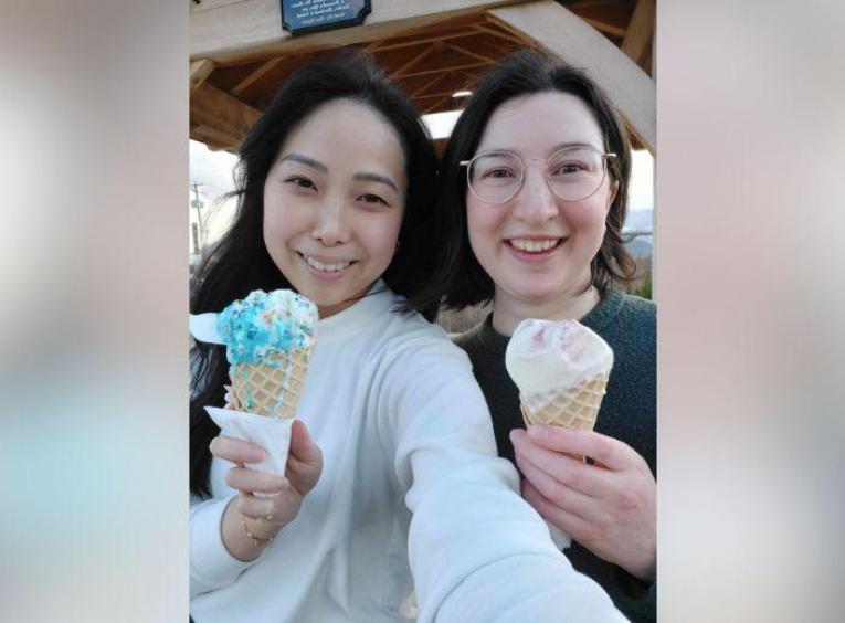 Two women smile while enjoying multi-coloured ice cream cones