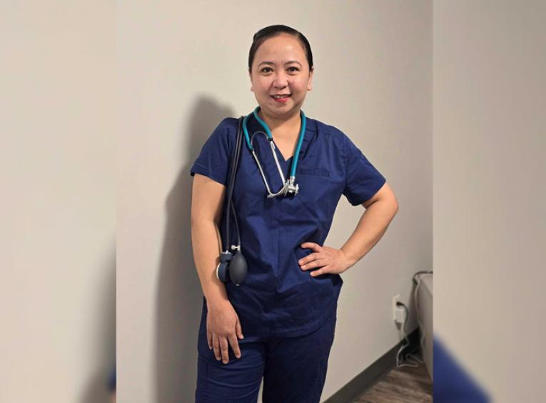 Woman in scrubs stands with one hand on hip