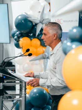 Man at podium with balloons around him.