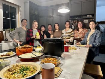 A group of women standing behind a kitchen counter.