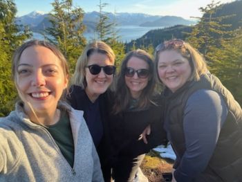 Kitimat SaferCare team posing, surrounded by trees, mountains and the ocean in the background.
