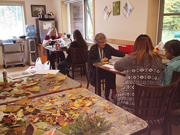 Seniors sit doing crafts together