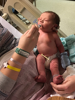 Newborn baby being fed by hand in hospital