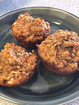 Three carrot bran muffins sit on a plate.