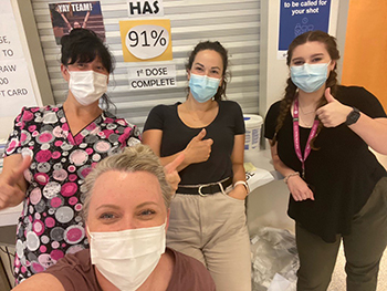 Group of women in masks give thumbs up