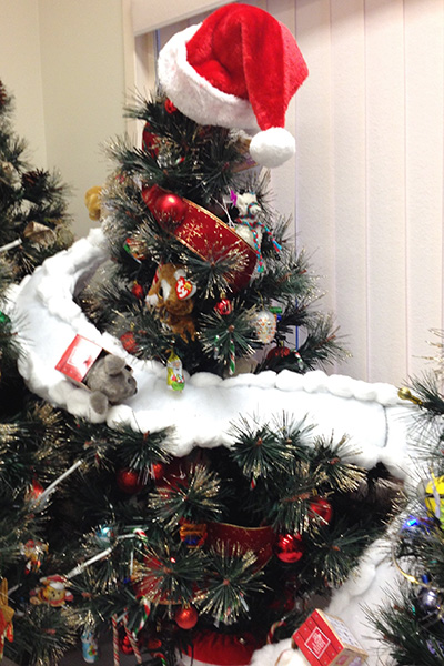 A small Christmas tree decorated with candy canes, TY stuffies, red balls, and a Santa hat on top.