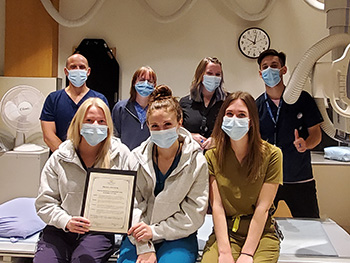 Group of people wearing masks sit in medical radiation technology department.