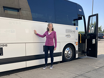 Woman stands beside large coach bus