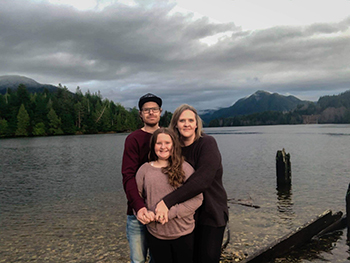 Family embrace for photo in front of mountain and lake. 