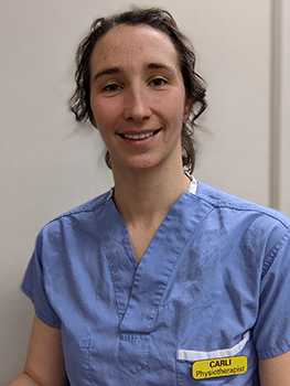 Woman in scrub uniform top with hair pulled back.