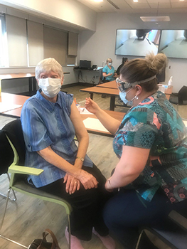 Nurse gives older woman vaccine in arm.