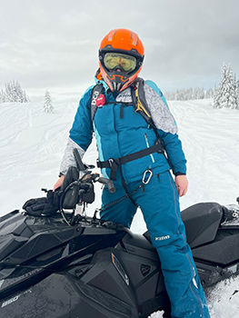 Person on snowmobile wearing safety gear