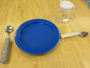 Accessible eating utensils beside a blue plate.