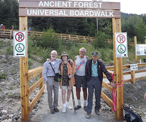 Four hikers at a trail entrance.