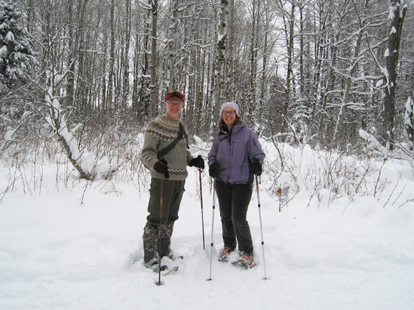 Man and woman standing in the snow with snowshoes on