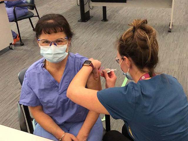 a woman with brown hair is given a vaccine from an immunizer