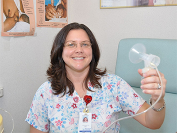 Woman in scrubs holds breast pump