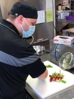 Bryce Dery, a Cook at Gateway Lodge, preparing radishes from the on-site garden.