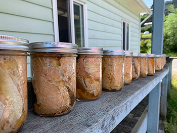 A row of freshly canned salmon, lined up along a wooden hand railing