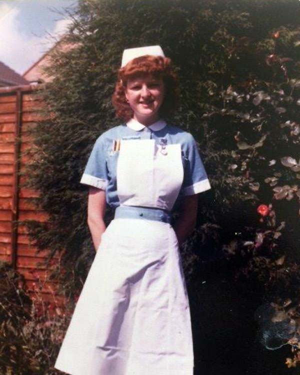 A young Cathy Czechmeister smiles in front of the camera, wearing a blue and white nursing uniform, including cap, from 1978.