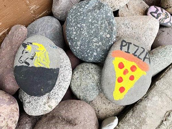 Rocks are painted, one with a cat face, another with pizza one it, and one more with a horse head. 