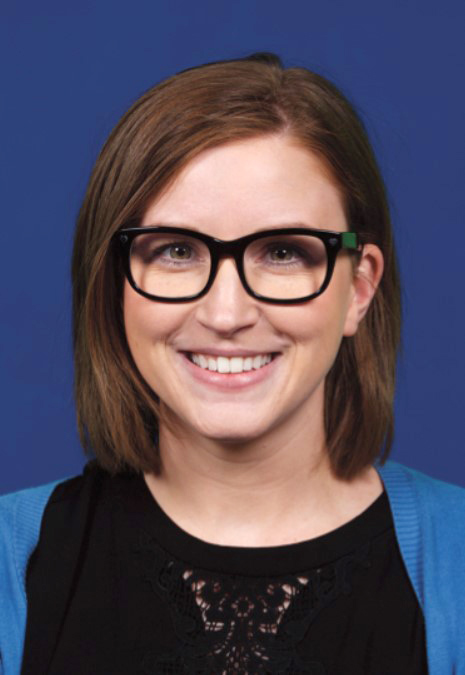 A woman with glasses smiles into the camera.