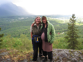 Two women standing together on rock over looking valley near Smithers, BC.