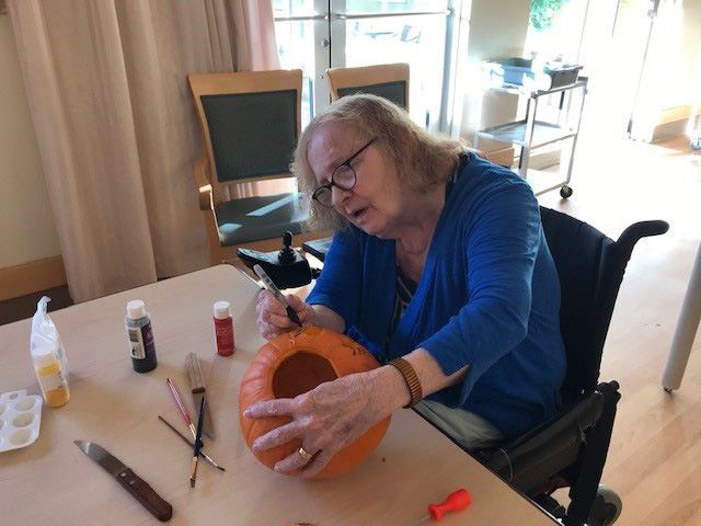 Older woman carving a pumpkin