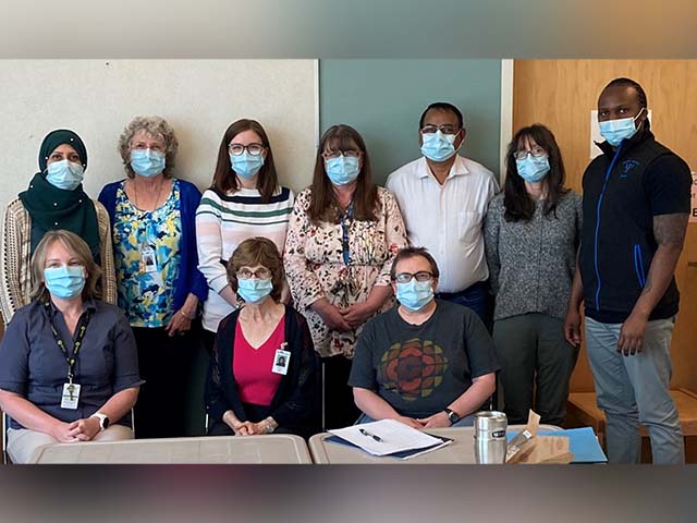 a group of people wearing masks pose for a group photo