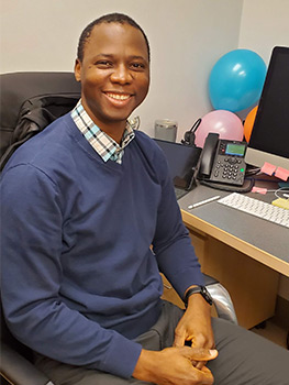 Man sitting in computer chair in front of a desk.