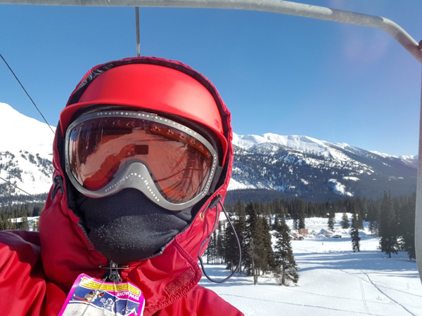 Selfie of Fara on the lift at Powder King, mountains in the background.