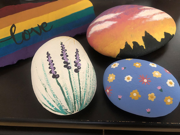 Four painted rocks have different designs on them.