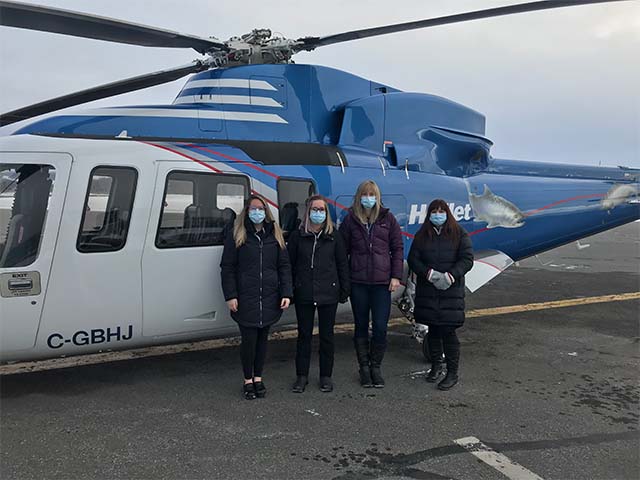 several people pose in PPE in front of a helicopter 