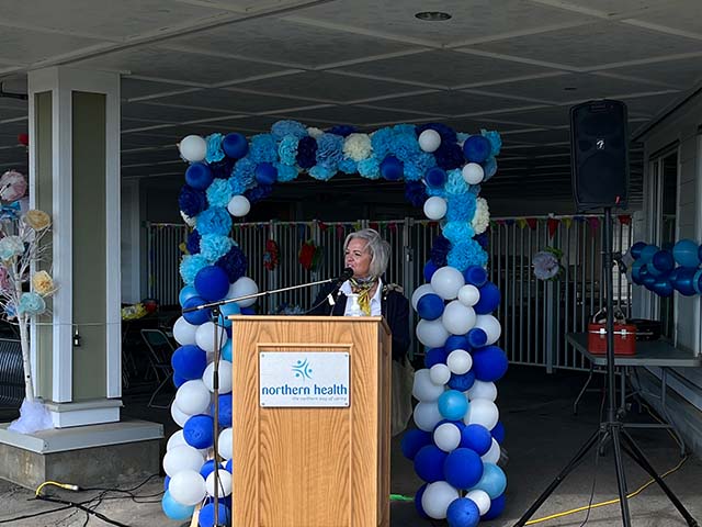 a woman with a blonde bob stands at the podium 