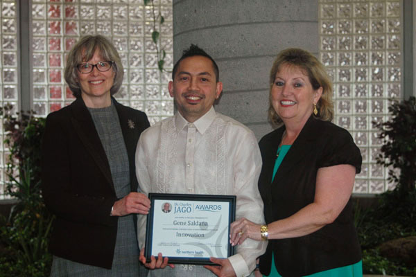 A man with a plaque award stands between two women.