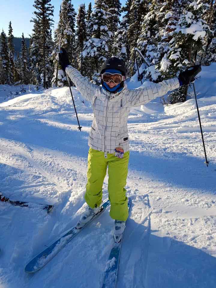 Woman skiing with arms raised high.