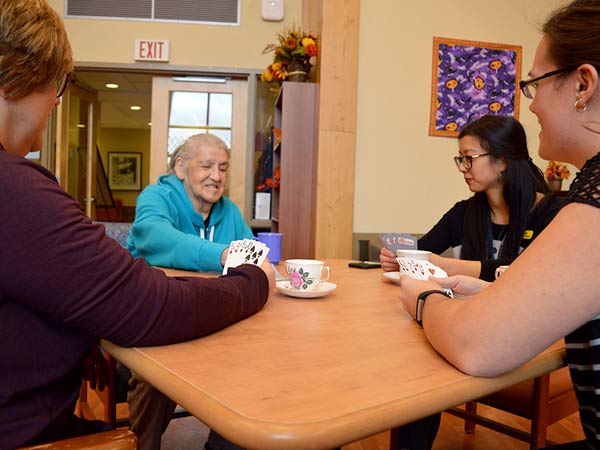 Three staff members play cards with a Gateway Lodge resident.