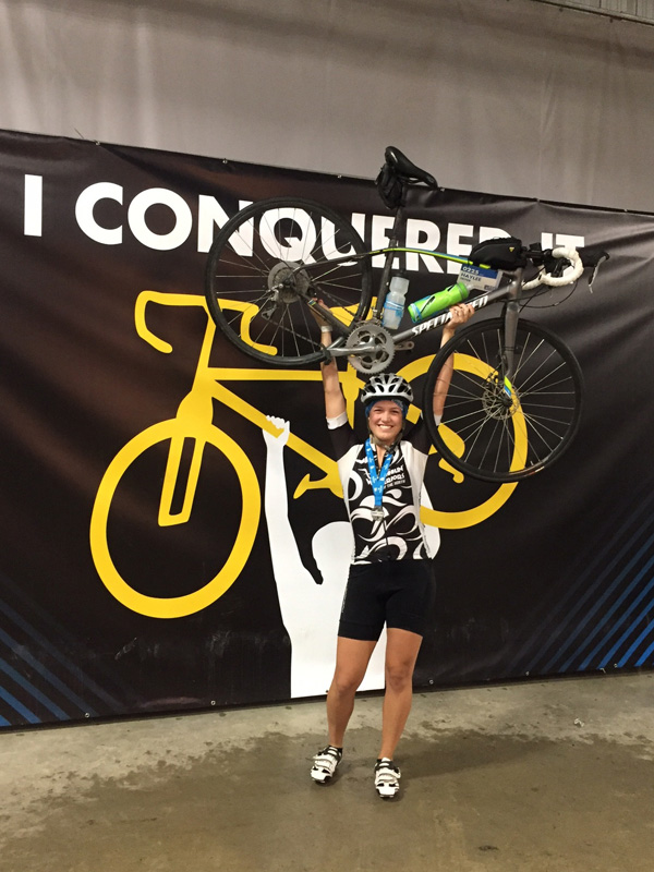 Haylee holding her bike above her head. 