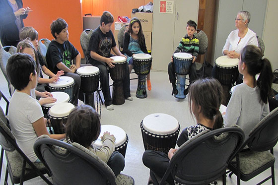 Students sitting in a circle with drums in front of each student.