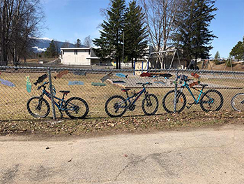 Bikes in a row locked to a fence.