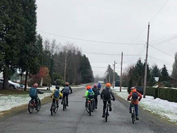 Children riding their bikes down the road.