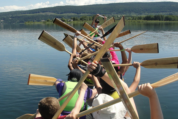 Paddlers in dragon boat with paddles raised.