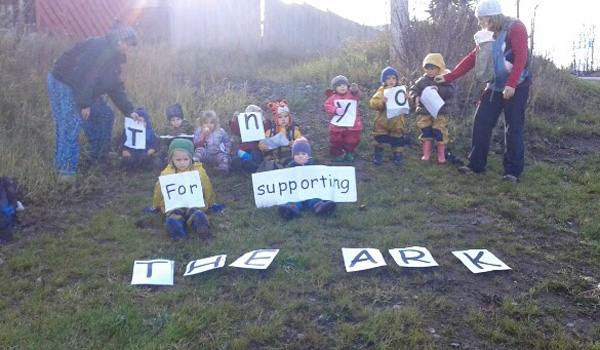 Children and caregivers outside holding signs.