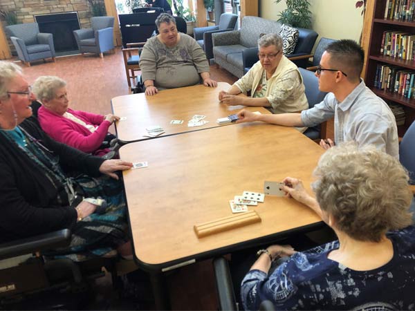 Five residents of Gateway Lodge play cards with a university student.
