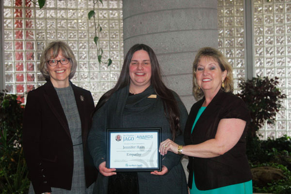 A woman holding a plaque award is standing between two other women.