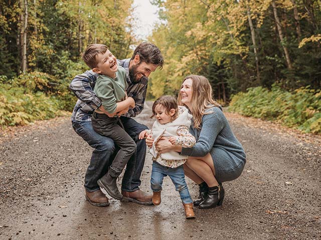 a family - man, two children, and woman stand on a road for a family photo in the fall